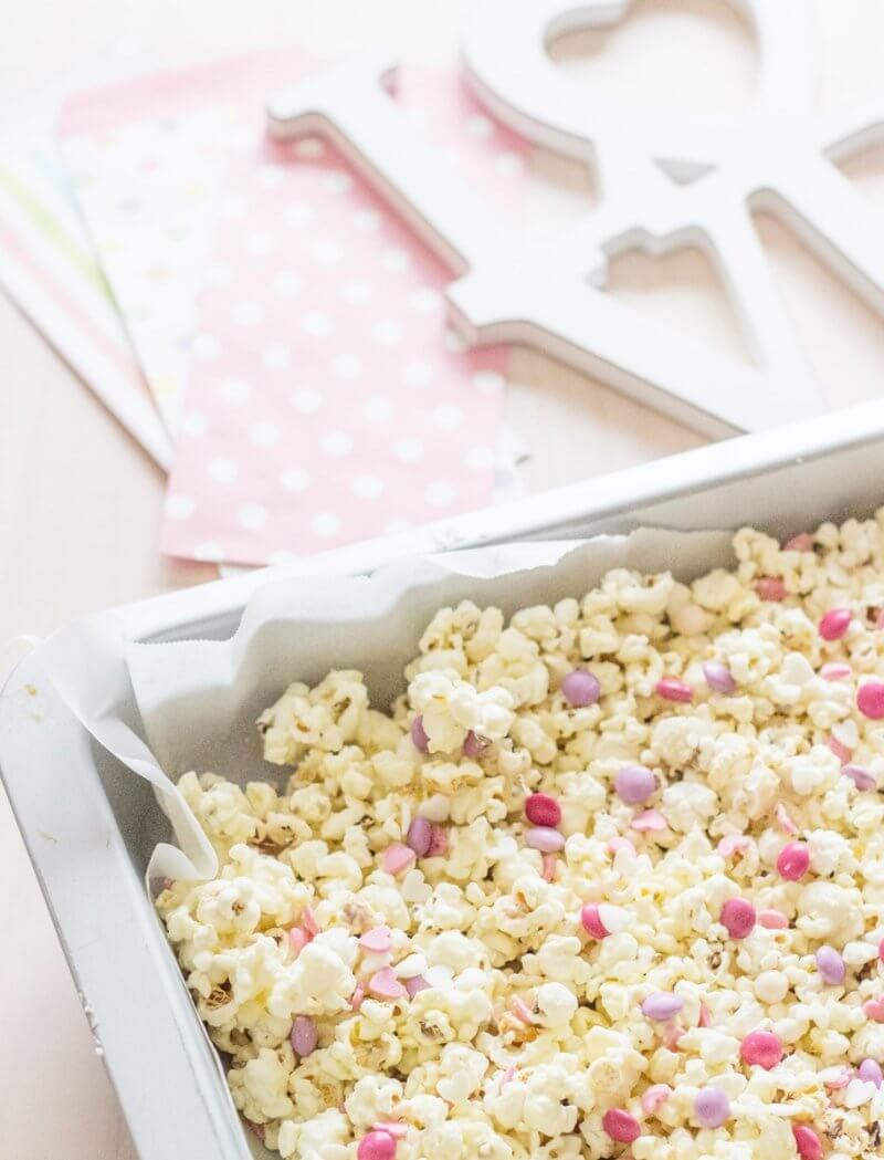 A super easy Valentines Day Gift! Valentines Popcorn made with salted popcorn, melted white chocolate, mini Smarties (M&M´s will do just fine too!) and edible heart confetti | FlavoursandFrosting.com