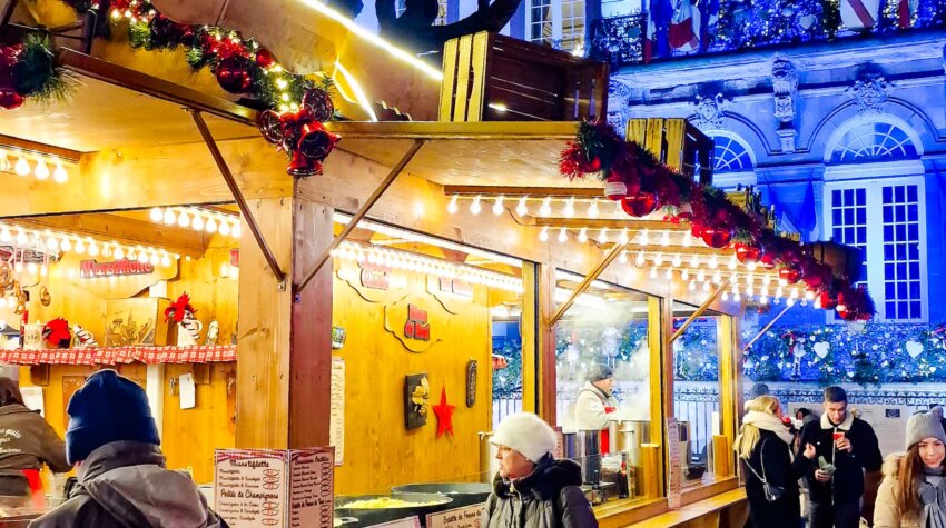 Christmas market stall in Strasbourg illuminated at night, showcasing festive decorations, twinkling lights, and holiday treats.