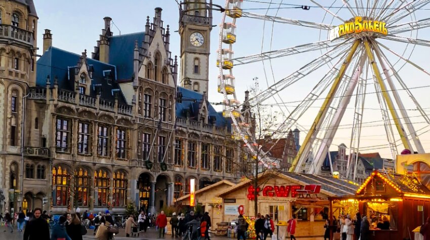 Ferris wheel behind a beautiful landmark and a Christmas market in Ghent
