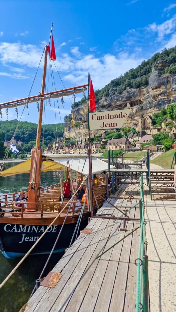Pirate style tour boat on the river waiting for passengers to get on, on a clear day with a cliff in the background