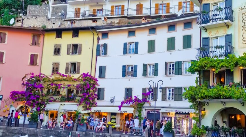 Colorful waterfront buildings and small boats docked at the harbor in Limone sul Garda, Lake Garda, Italy.