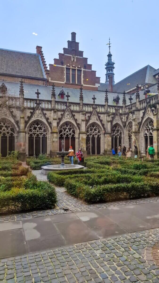 The Pandhof cloister garden of St. Martin’s Cathedral in Utrecht, a peaceful medieval herb garden surrounded by a 15th-century cloister with a central fountain and statue of Hugo Wstinc.