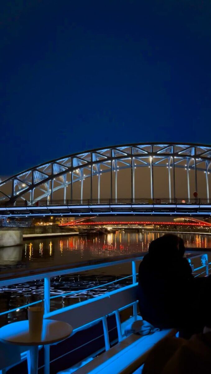 Boat tour at night on the Vistula River in Krakow going under a bridge