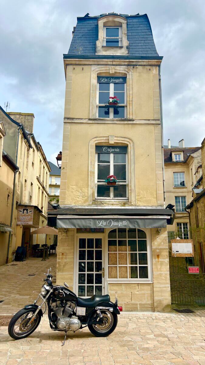 This image shows La Vaugette, a distinctive narrow, four-story stone building in Caen, France, currently housing a crêperie.