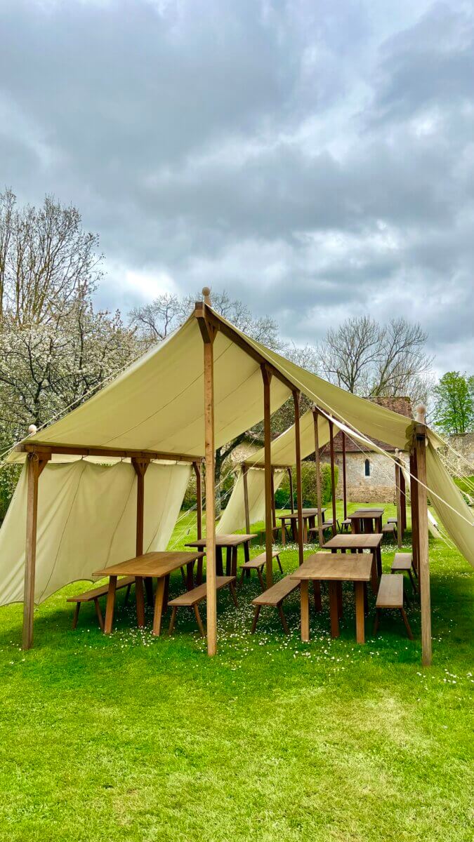 This image features a traditional marquee tent set up outdoors for a medieval event.