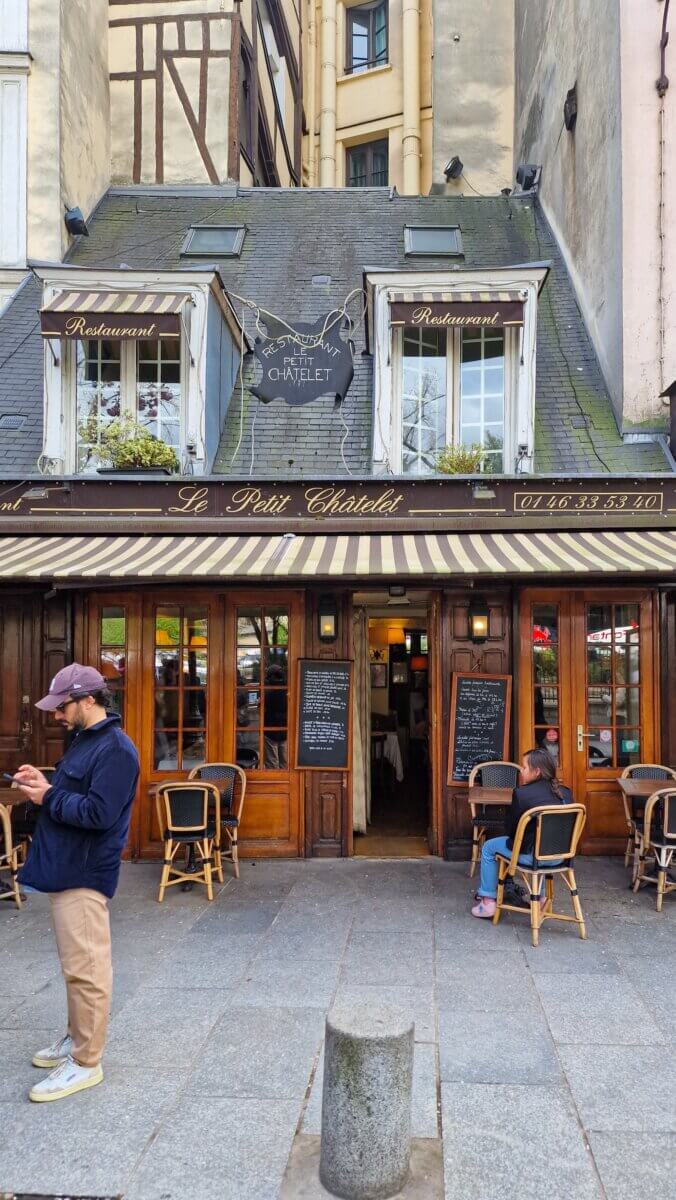 This is the storefront of Le Petit Châtelet, a historic French restaurant in Paris known for its medieval architecture and striped awnings.