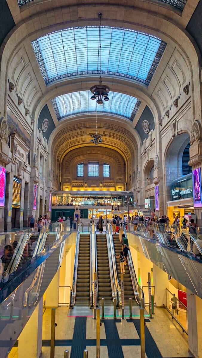 This photo shows the main interior hall and escalators inside the Milano Centrale railway station in Milan, Italy